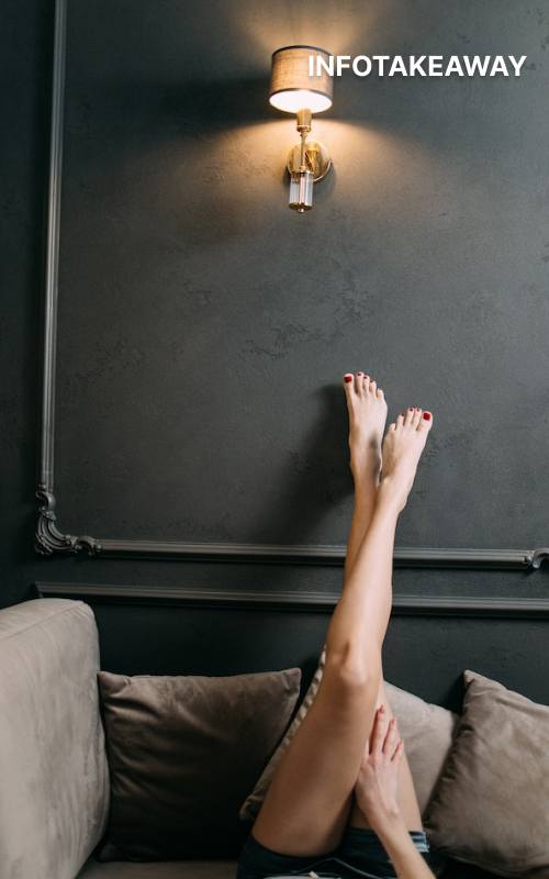 Woman lying on sofa with feet against black wall