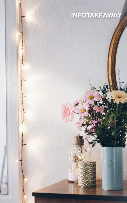 String lights hanging on wall beside flowers